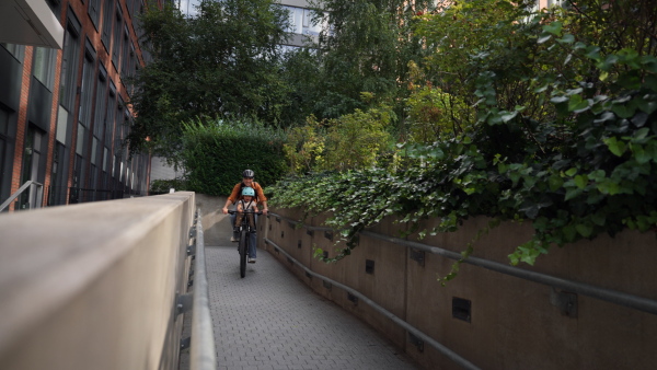 Mother carring her son on a secure child bike carrier or seat, both wearing helmets. Mom commuting with a young child through the city on a bicycle.