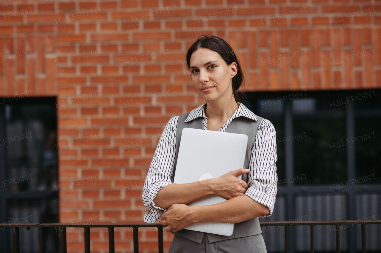 Portrait of beautiful woman in business attire standing on city street. Female university professor in front of university building.