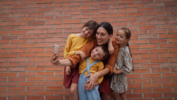 Video of mom picking up children from school. Mom taking a selfie with her kids in front of the school building.