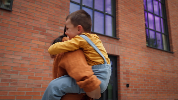 A hard-working, ambitious mother picking up son from school, greeting him in front of the school building, and heads to work. Concept of work-life balance for women.