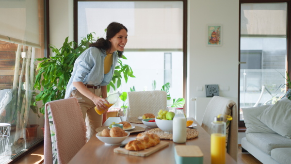 Mother prepares breakfast and pouring juice for the children, in the morning. Maternal love and care for the household and family.