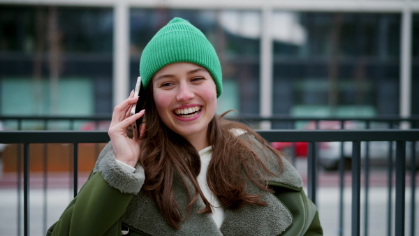 A beautiful young woman making phone call, walking on city street.