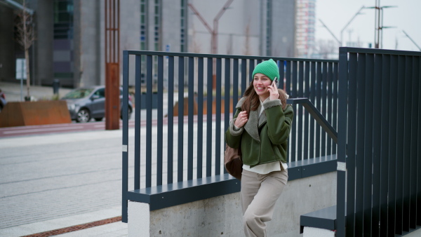 A beautiful young woman making phone call, walking on city street.