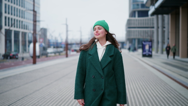 A beautiful woman walking through city. Woman in the city during cold spring day.