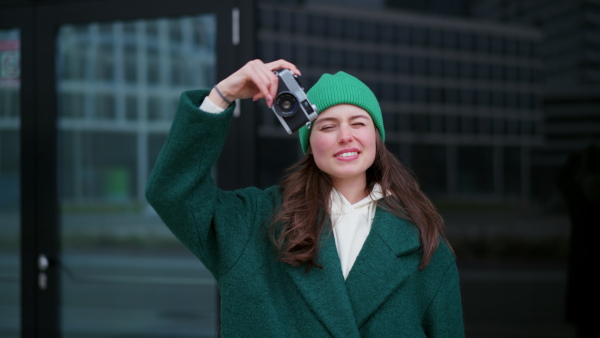 Video of beautiful young photographer taking photos of city. Fashionable Gen z woman holding camera, enjoying architecture spring cityscape.