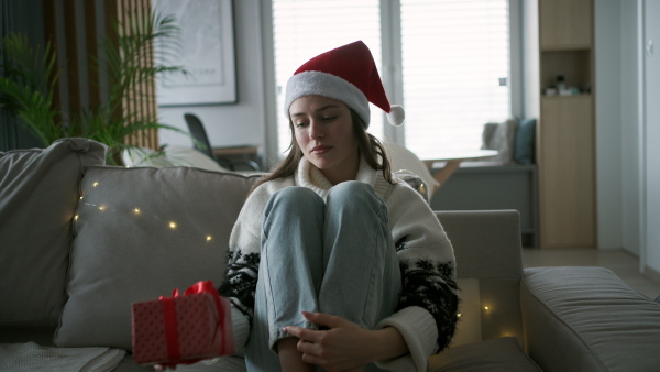 A beautiful woman holding a wrapped gift in her hand, opening it and smiling. A Christmas surprise or birthday gift from a friend delivered by mail.