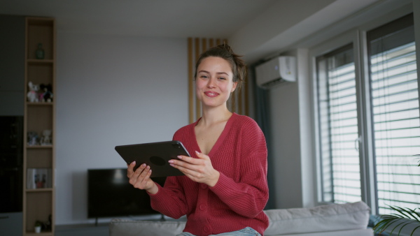 A woman with tablet managing household functions of smart home system. Online shopping, e-commerce.