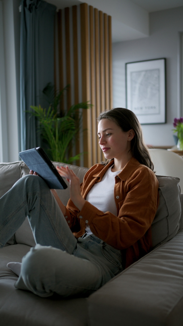 A woman with tablet managing household functions of smart home system. Online shopping, e-commerce.