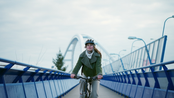 A young urban woman traveling around the city by bike, cycling to work, university to save money. Concept of bike commuting in the city, sustainable lifestyle.