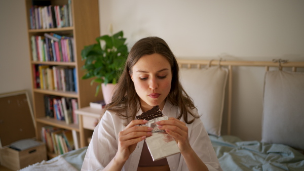 Enjoying chocolate. Woman has cravings for chocolate, eating with closed eyes.