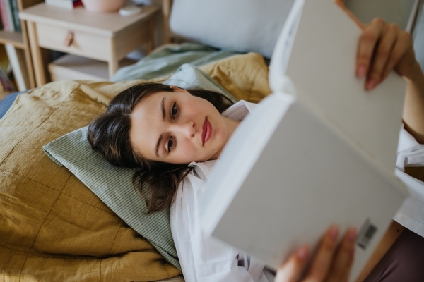 Beautiful woman reading book in bed, cozy feeling. Freedom, weekend activity for single woman.