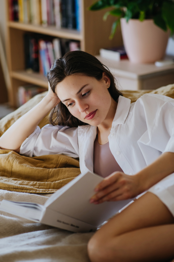 Beautiful woman reading book in bed, cozy feeling. Freedom, weekend activity for single woman.