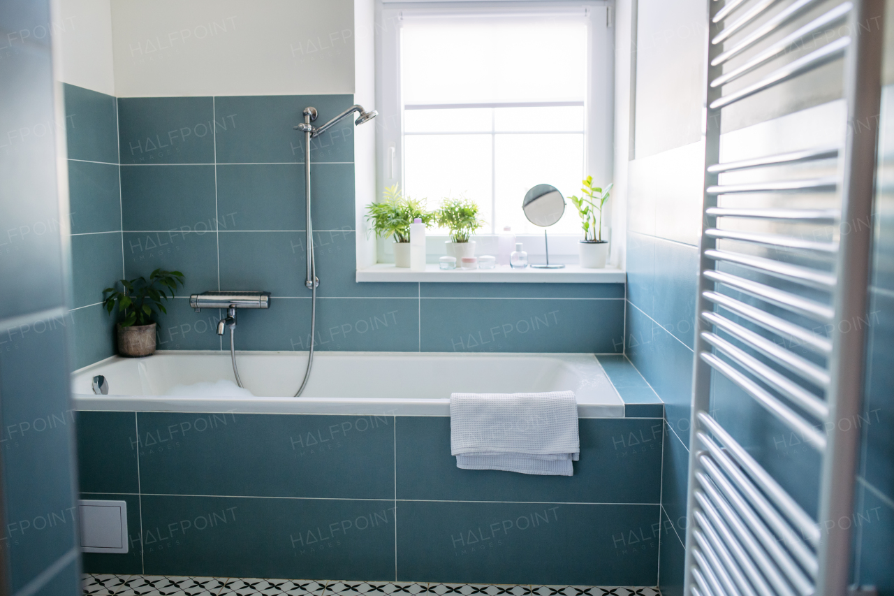 Modern and minimalistic bathroom with a blue tile wall and tile floor and a white bathtub.