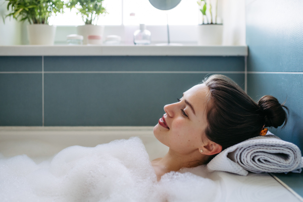 Beautiful woman relaxing in warm bathwater, soaking in bathtub. Enjoying bubble bath with closed eyes.