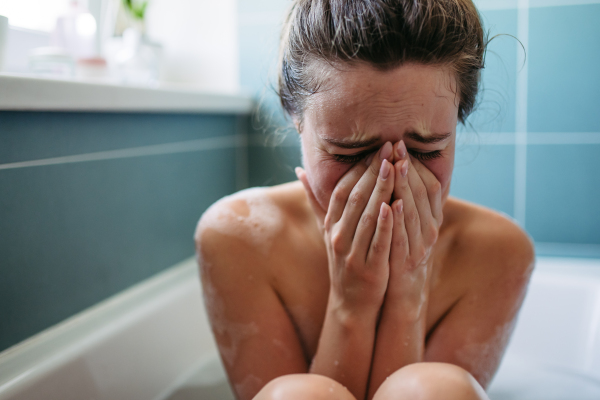 Crying, depressed woman in bathtub. Young woman feeling hopeless, having problems with harassment, rude comments in work.