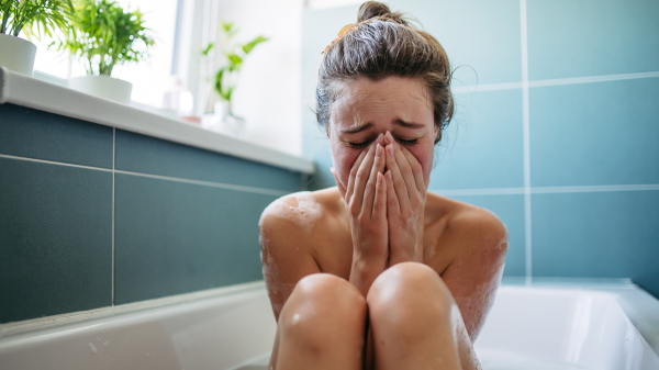 Crying, depressed woman in bathtub. Young woman feeling hopeless, having problems with harassment, rude comments in work.