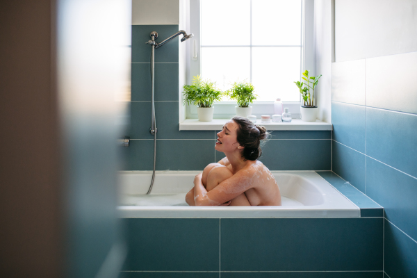 Crying, depressed woman in bathtub. Young woman feeling hopeless, having problems with harassment, rude comments in work.