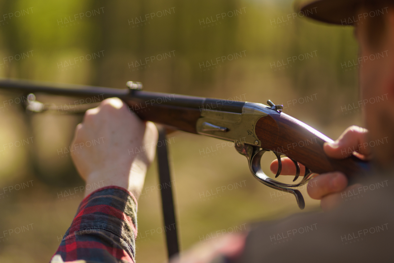 A hunter man aiming with rifle gun on prey in forest.