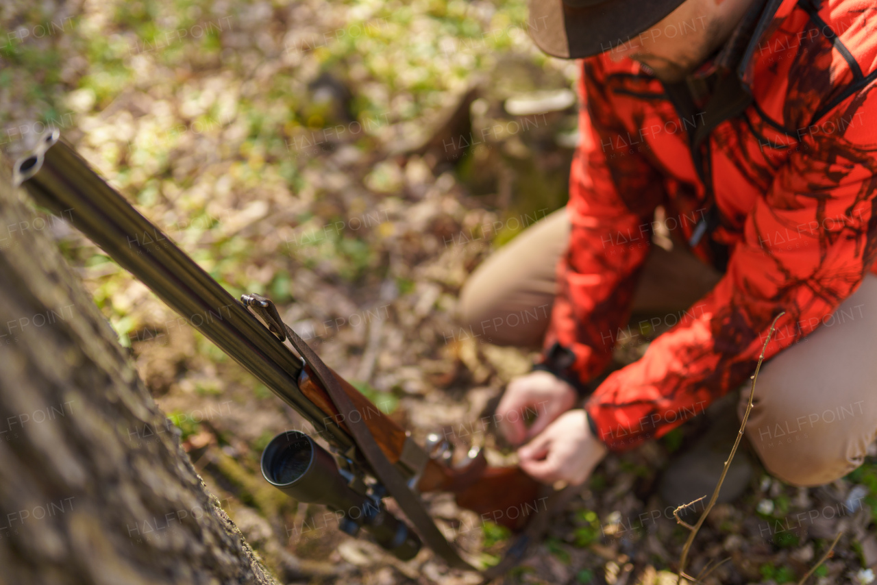 A hunter man with rifle gun waiting for prey in forest.