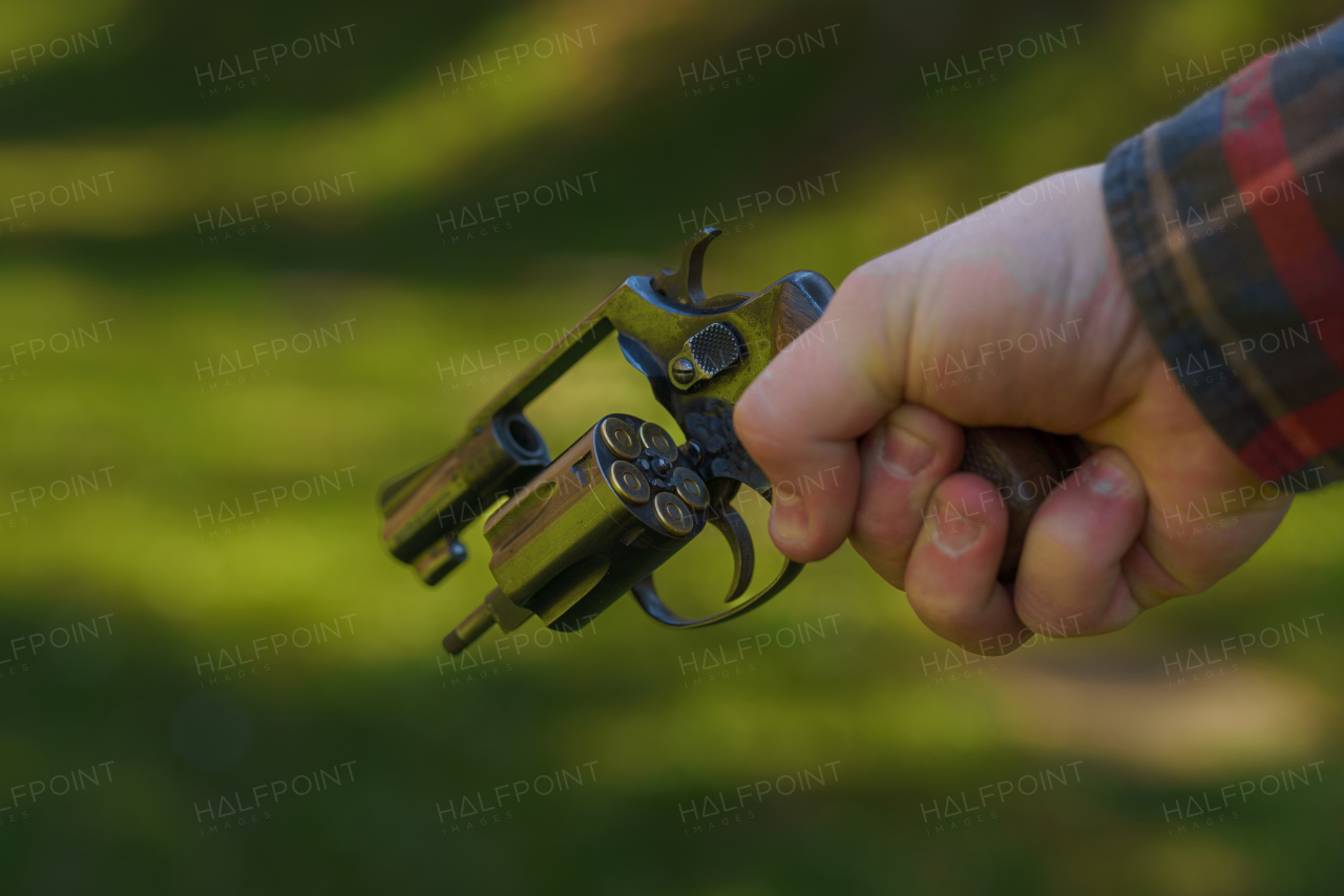 An unrecognizable man holding revolver with full cartridge in the drum Close-up.