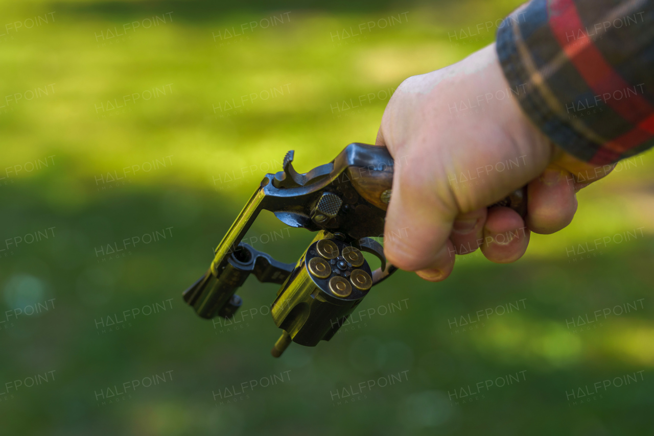 An unrecognizable man holding revolver with full cartridge in the drum Close-up.