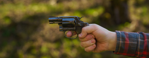 An unrecognizable man with revolver aiming target on shooting range training outdoors.