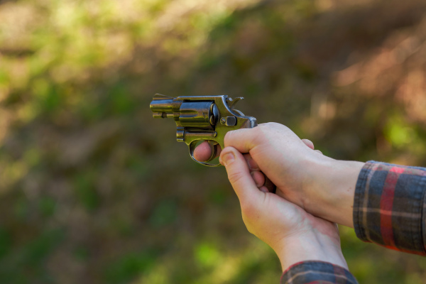 An unrecognizable man with revolver aiming target on shooting range training outdoors.