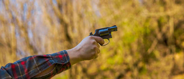 An unrecognizable man with revolver aiming target on shooting range training outdoors.