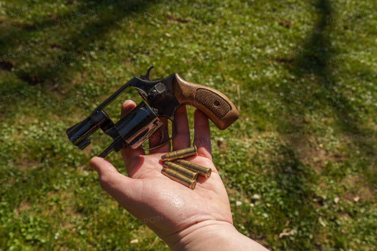 An unrecognizable man holding revolver with bullets in his hand, Close-up.