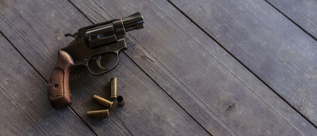 A revolver with bullets on the wooden table.