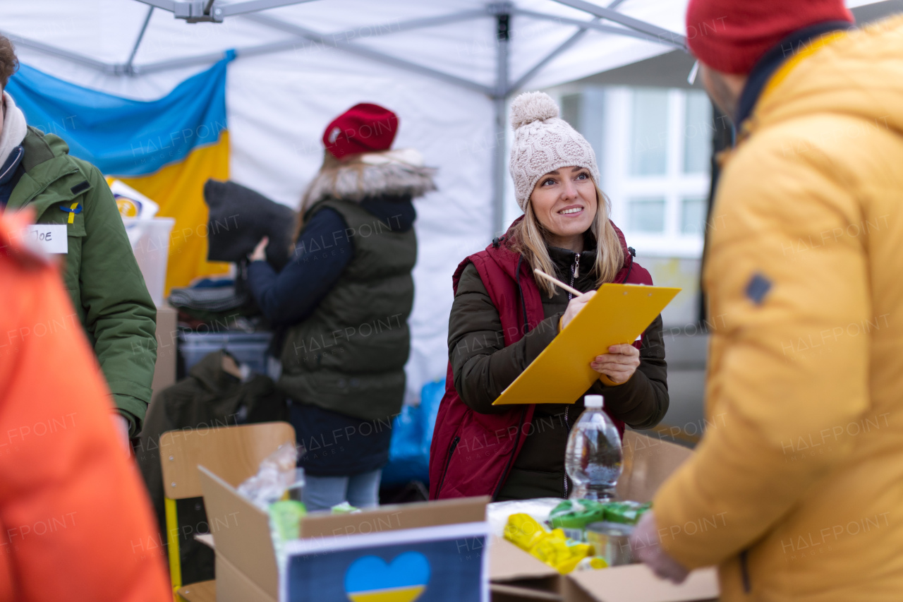 The volunteers distributing food and drink to refugees on the Ukrainian border, humanitarian aid concept.