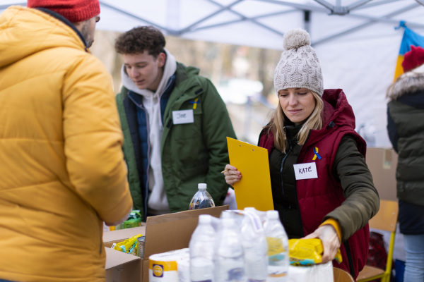 The volunteers distributing food and drink to refugees on the Ukrainian border, humanitarian aid concept.