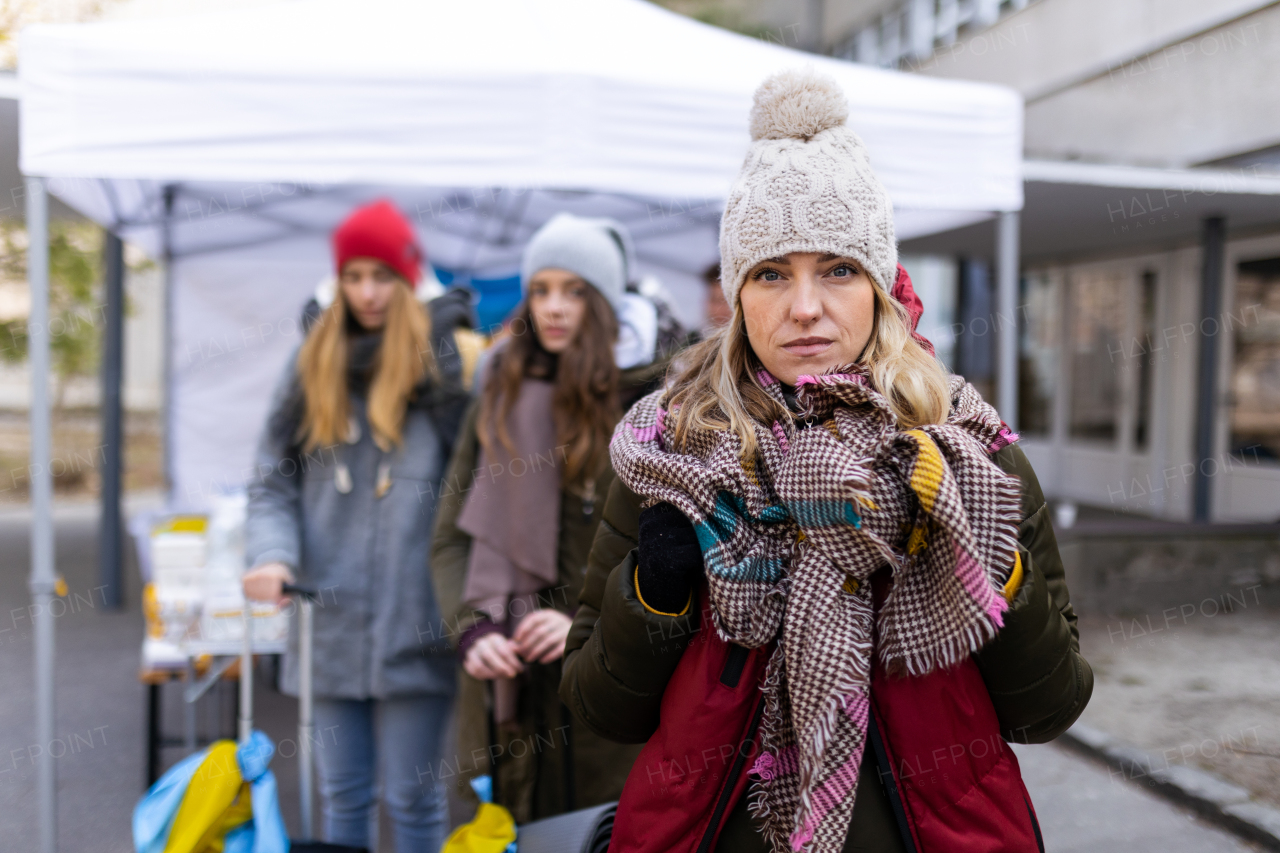 A depressed Ukrainian refugee woman crossing border and looking at camera.