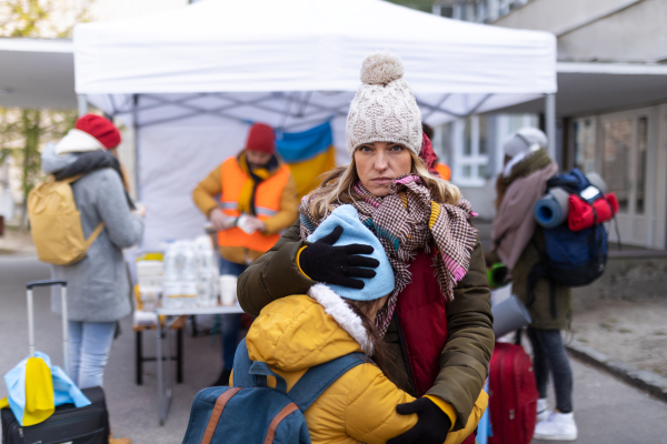 The Ukrainian refugee mother with child crossing border and looking at camera.