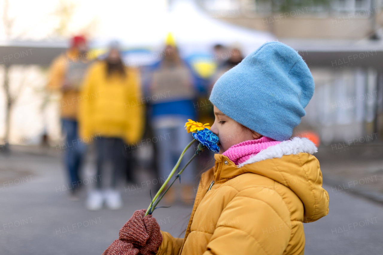 A lIttle girl holding yellow and blue flowers. Protest against Russian invasion of Ukraine.