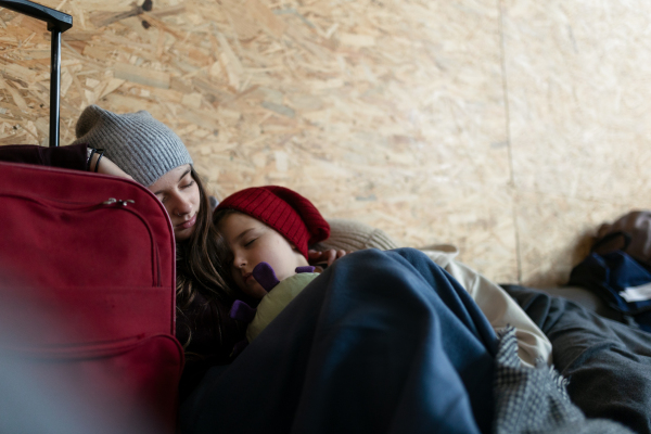 The Ukrainian war refugees in temporary shelter and help center, children tired and sleeping.