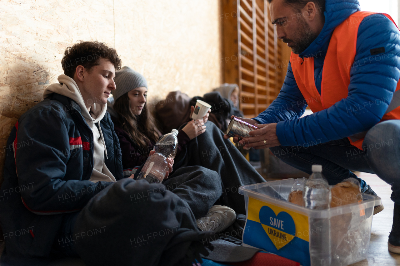 Ukrainian war refugees in a temporary shelter and help center getting drinks from volunteers.