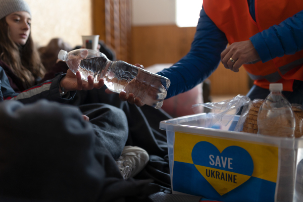 Ukrainian war refugees in a temporary shelter and help center getting drinks from volunteers.