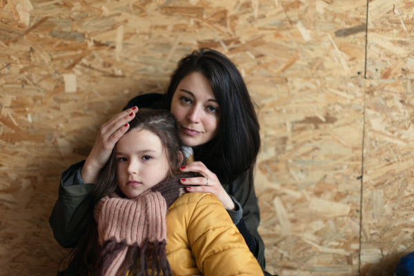 Ukrainian war refugees in temporary shelter and help center, a little girl with her mother.