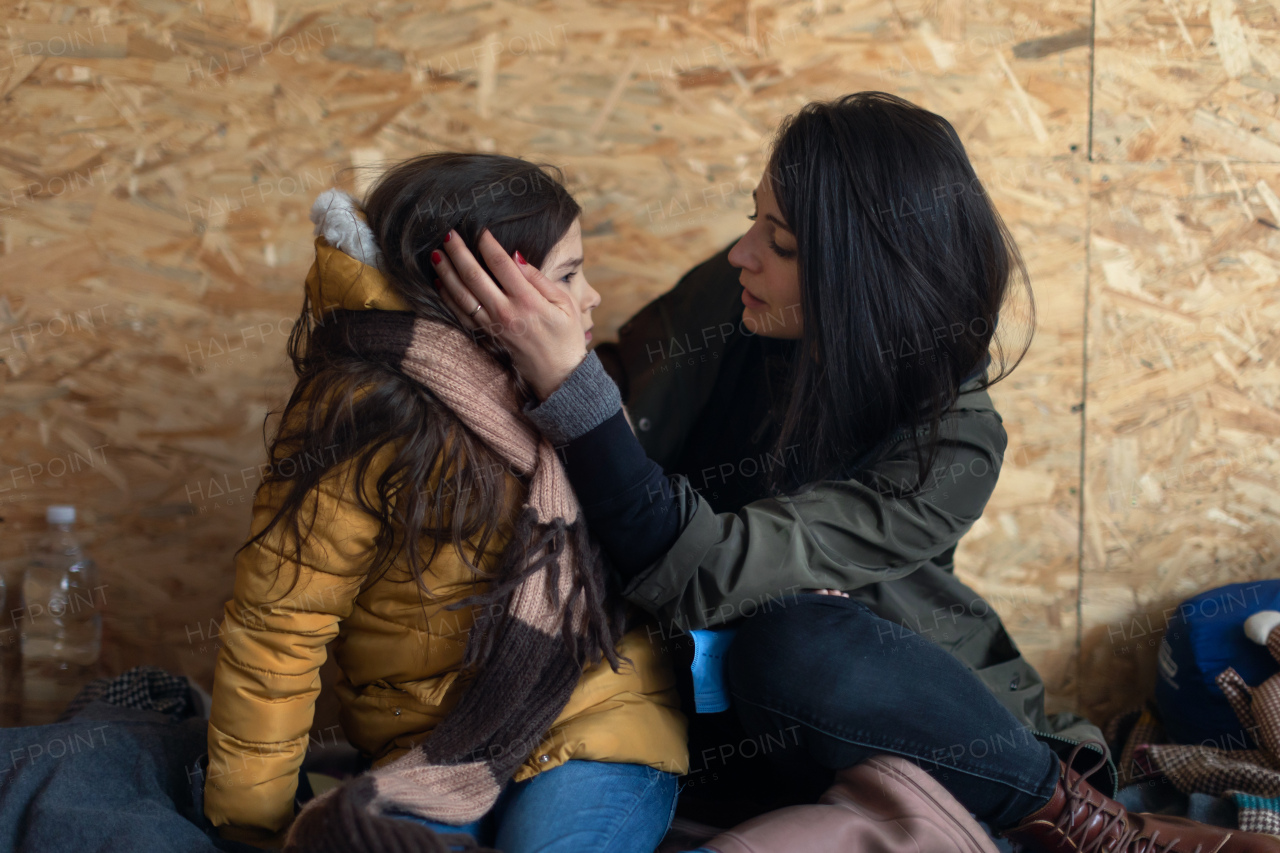 Ukrainian war refugees in temporary shelter and help center, a little girl with her mother.