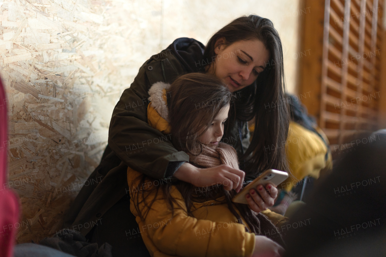 Ukrainian war refugees in temporary shelter and help center, a little girl with her mother.