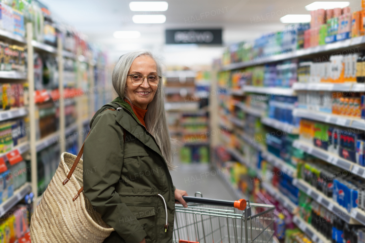 An elder woman standing and shopping in supermarket.