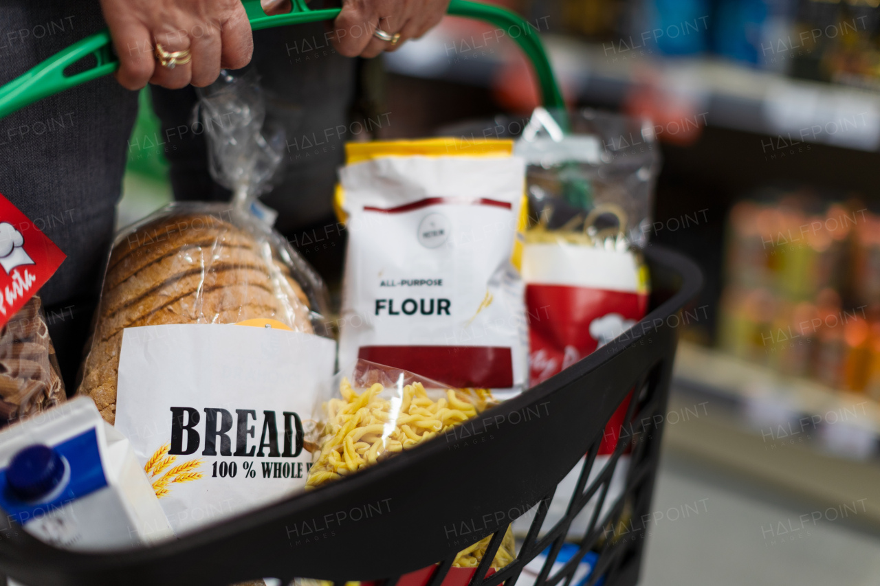 Woman shopping at the supermarket, she is carrying full shopping basket