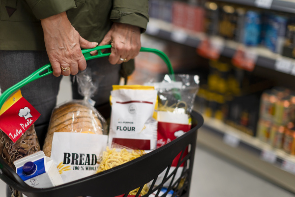 Woman shopping at the supermarket, she is carrying full shopping basket