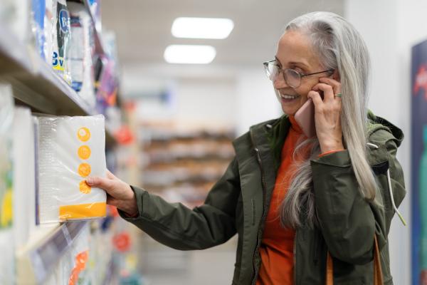 Elder woman choosing and buying drugstore goods in supermarket.