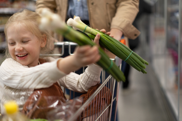 A little girl sitting in the trolley during family shopping in hypermarket