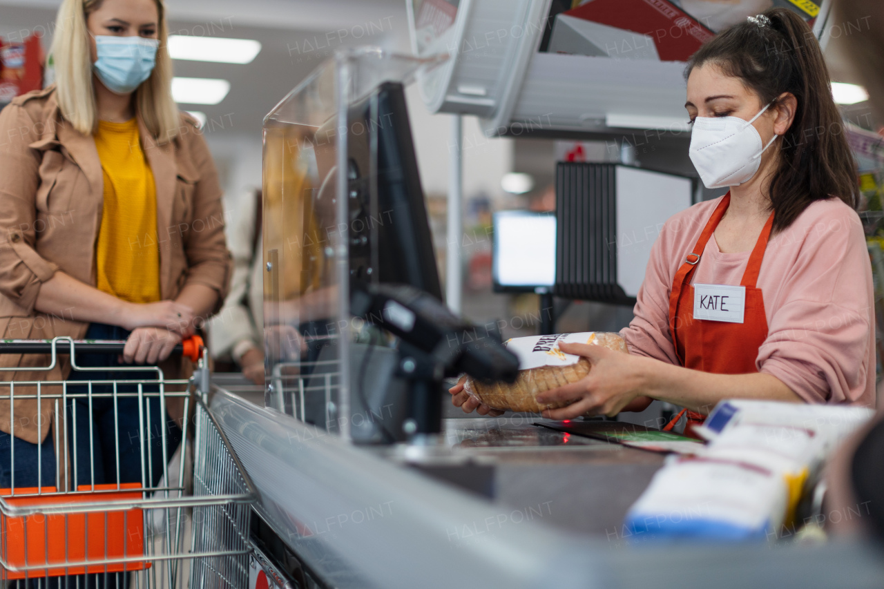 Checkout counter cashier scans bread in supermarket.