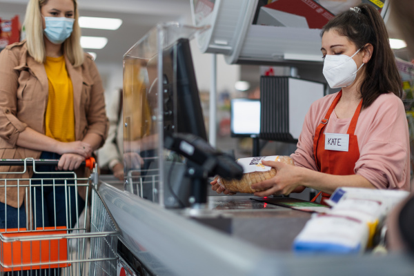 Checkout counter cashier scans bread in supermarket.