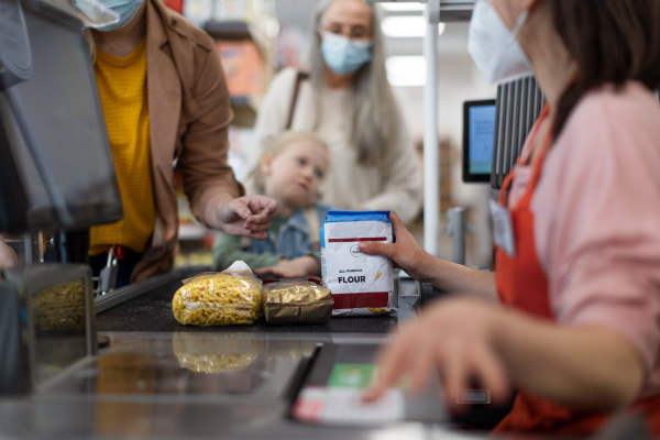 A checkout counter hands of the cashier scans groceries in supermarket.