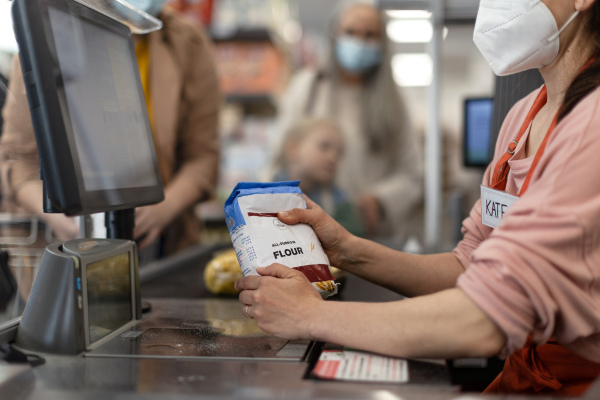 A checkout counter hands of the cashier scans groceries in supermarket.